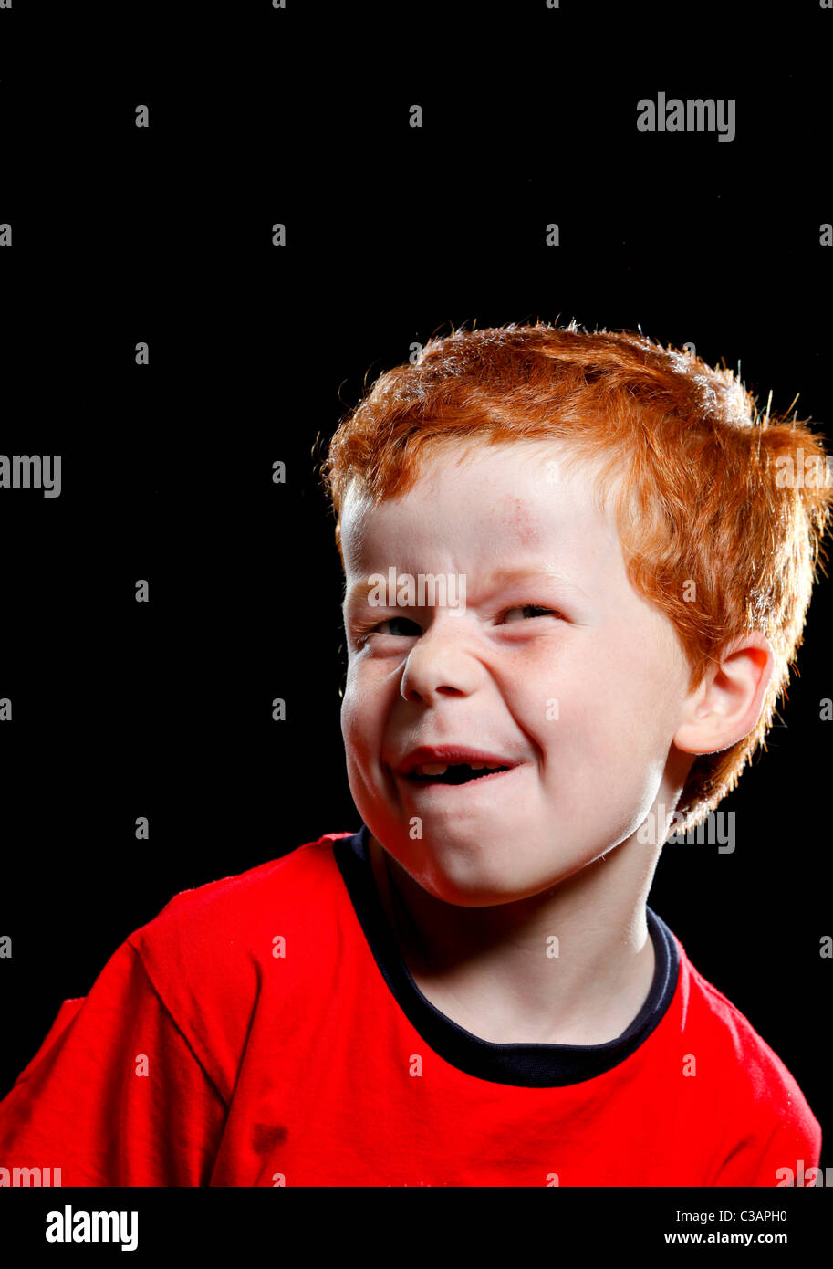 Ein sieben Jahre alter Junge ziehen ein lustiges Gesicht in Richtung der Kamera. Stockfoto