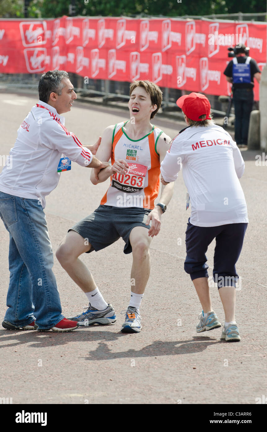 Einstürzenden Konkurrent unterstützt durch Ärzte beim London-Marathon medizinische Aufmerksamkeit geschenkt. London-Marathon 2011 Stockfoto