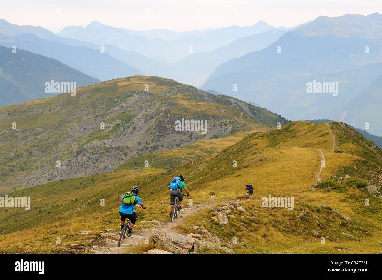 Drei Mountainbiker fahren entlang einer Strecke auf einem Bergrücken hoch hinauf in das Skigebiet von Méribel in Frankreich. Stockfoto
