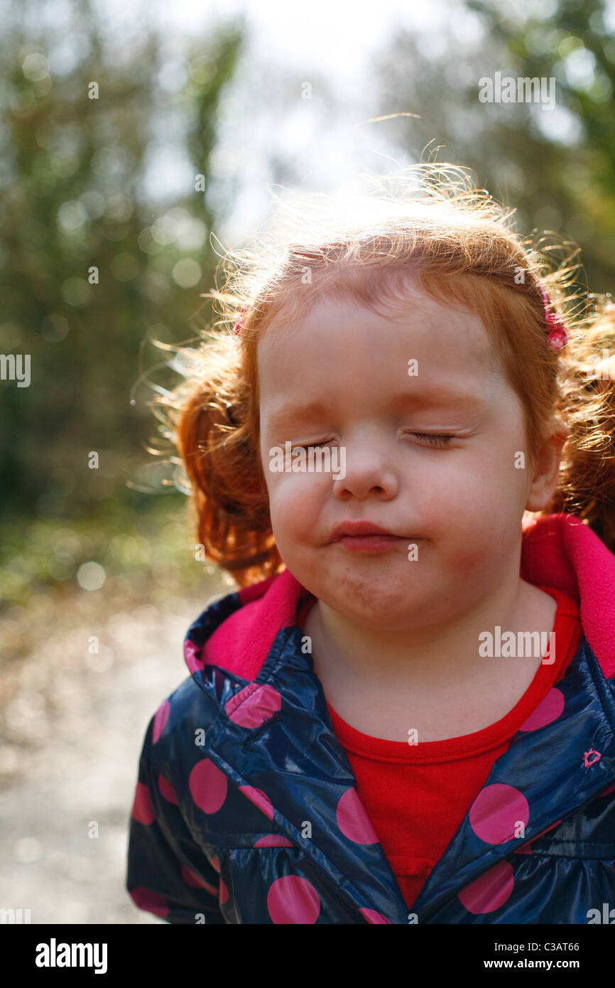 Ein 4 Jahre altes Mädchen mit Ingwer Haar in Zöpfen schauen verwirrt. Stockfoto
