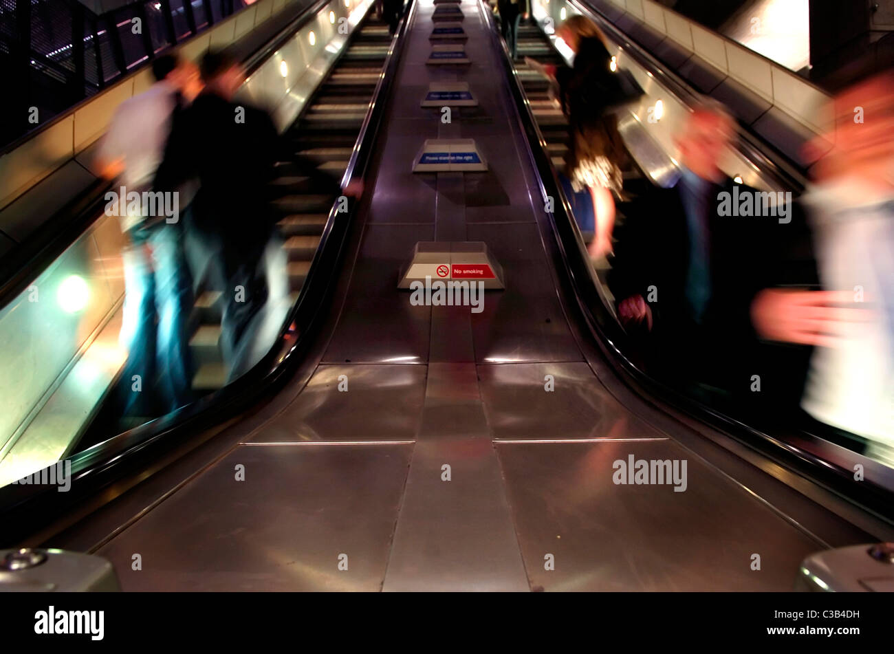 Menschen mit den Rolltreppen führen in und aus einer unterirdischen Plattform Stockfoto