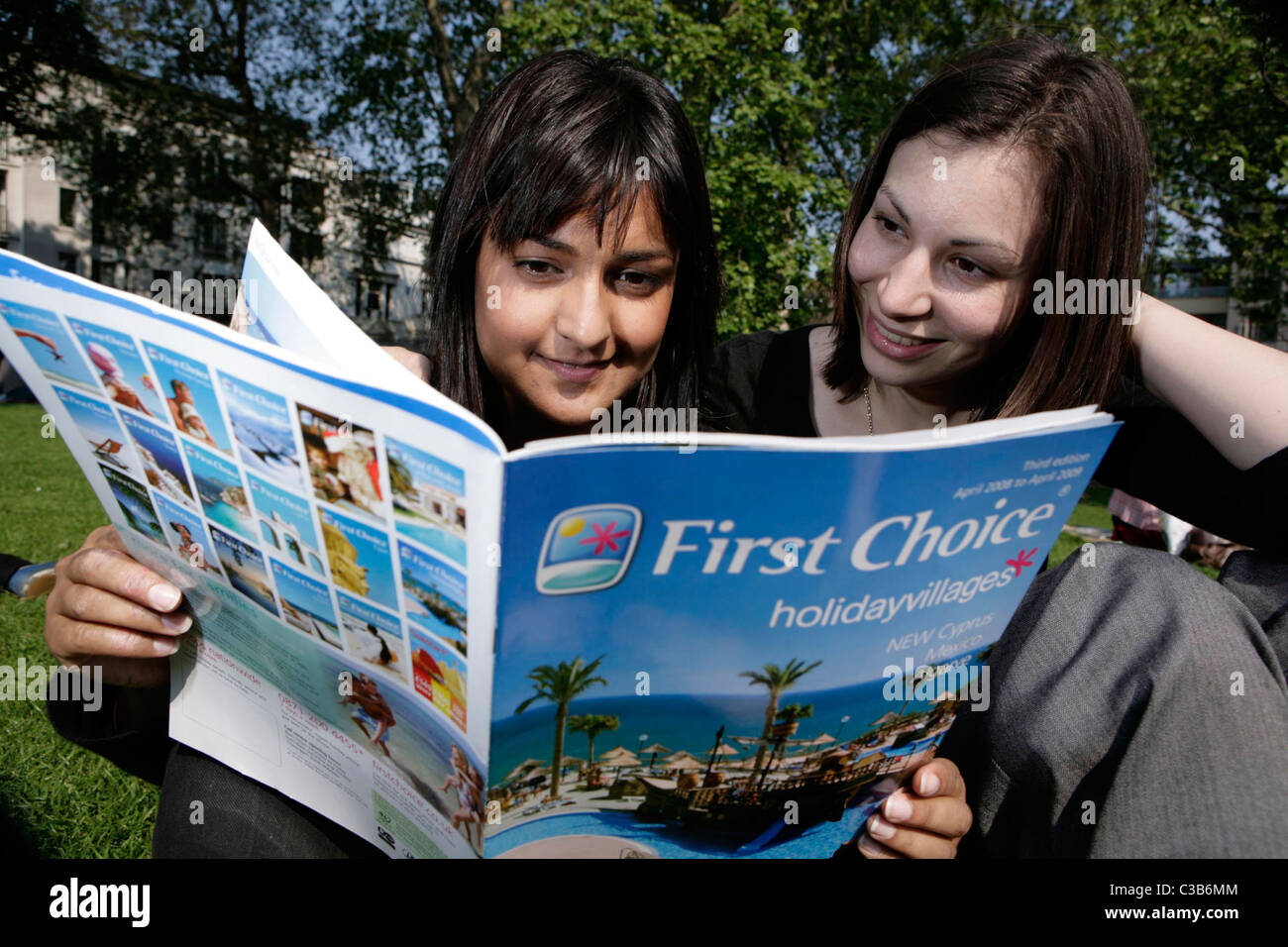 Zwei Frauen, die durch eine erste Wahl Feriendörfer-Broschüre. Stockfoto