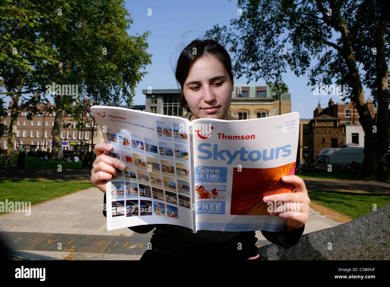 Eine Frau liest eine Thomson Skytours-Broschüre. Stockfoto