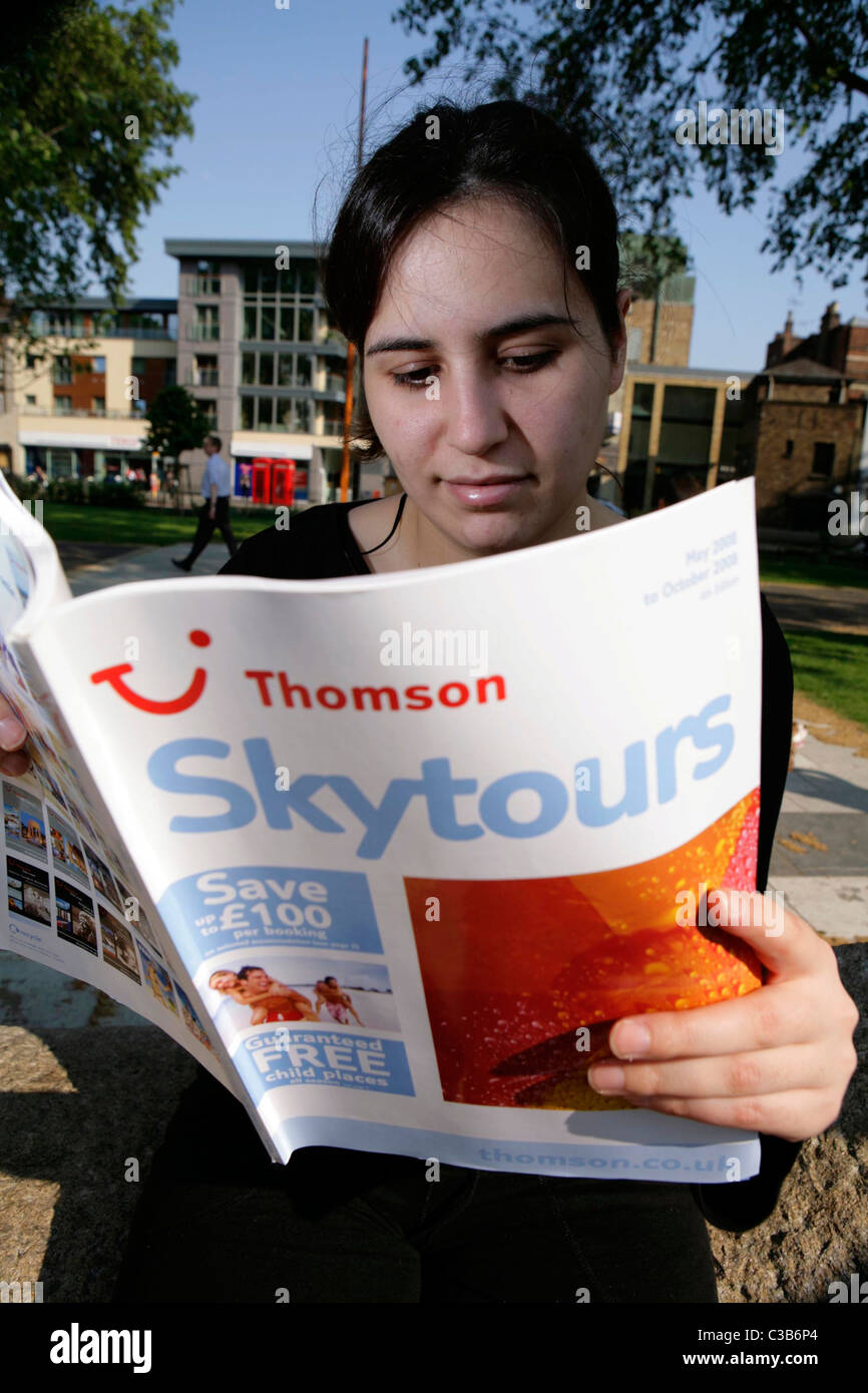 Eine Frau liest eine Thomson Skytours-Broschüre. Stockfoto