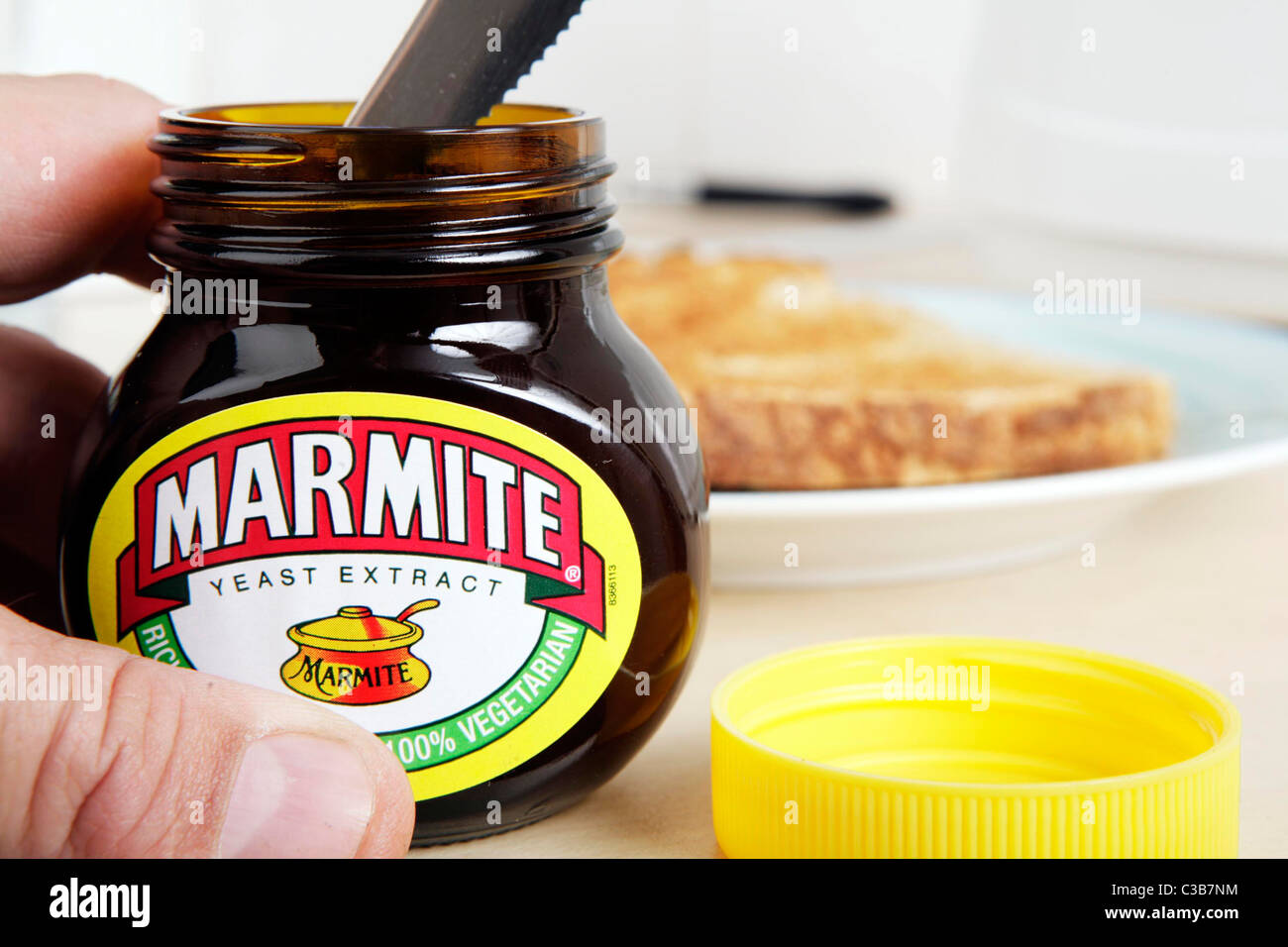 Ein Mann immer Marmite aus dem Glas mit einem Messer. Stockfoto