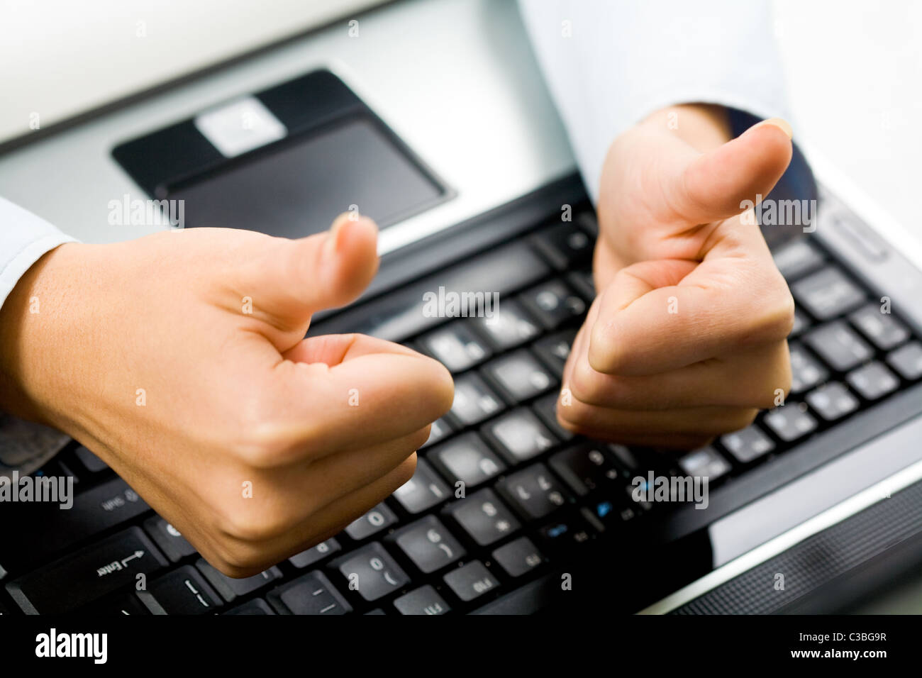 Nahaufnahme der weiblichen Hände mit Daumen hoch über Laptop-Tastatur am Arbeitsplatz Stockfoto