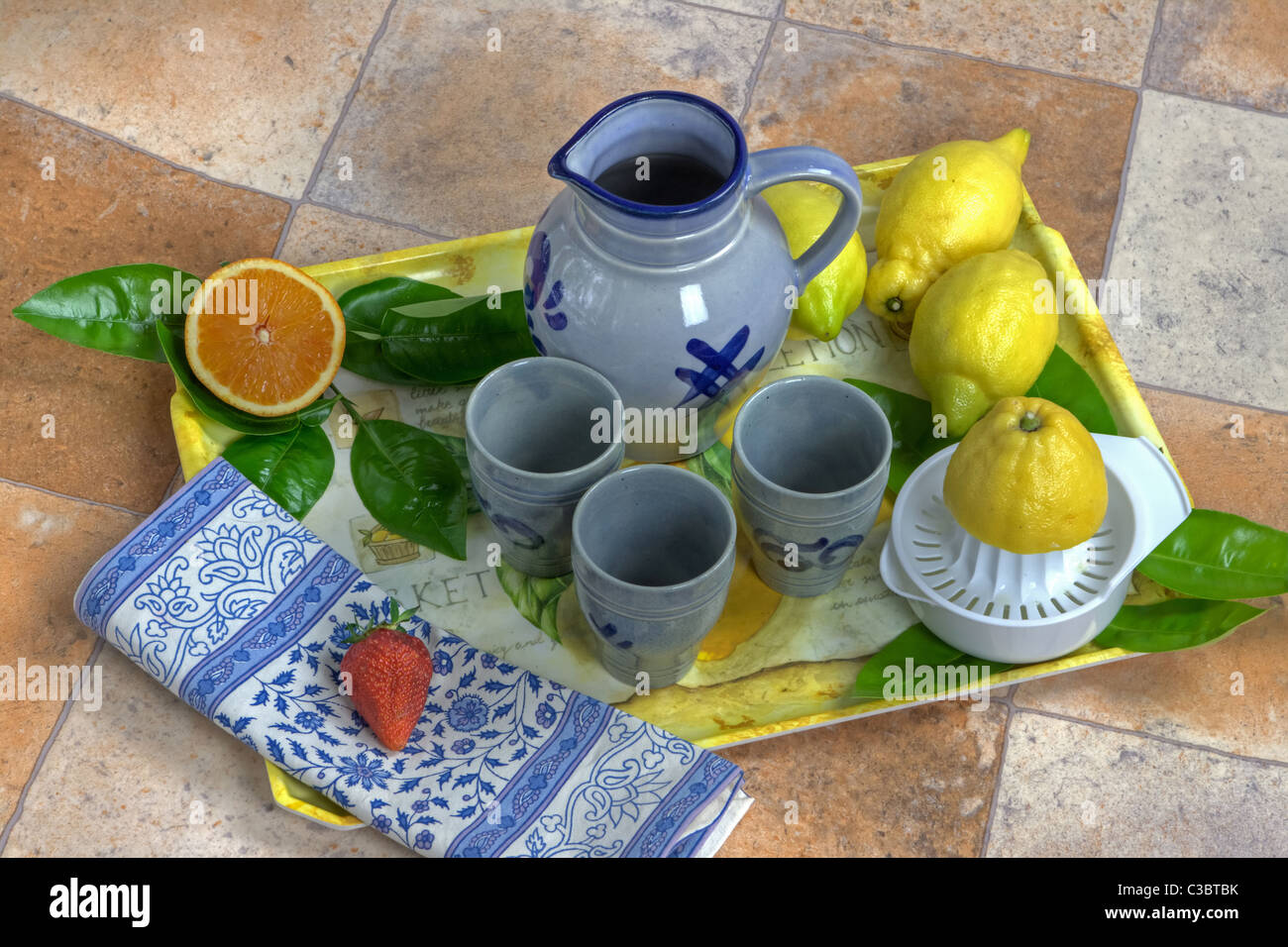 Tablett mit Zitronen, Orangen, Apfel und einen Krug und Becher Stockfoto