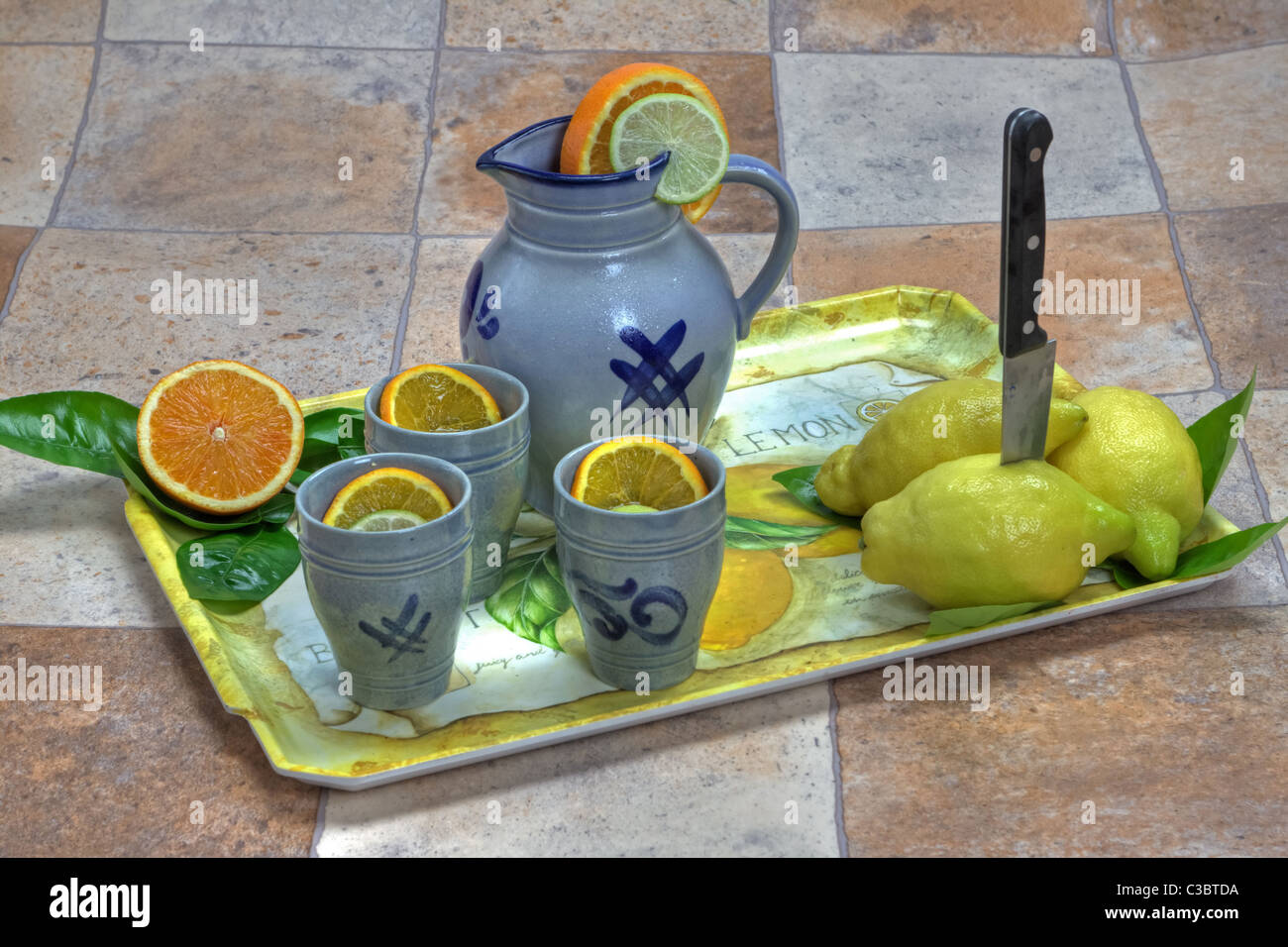Tablett mit Zitronen, Orangen, Apfel und einen Krug und Becher Stockfoto