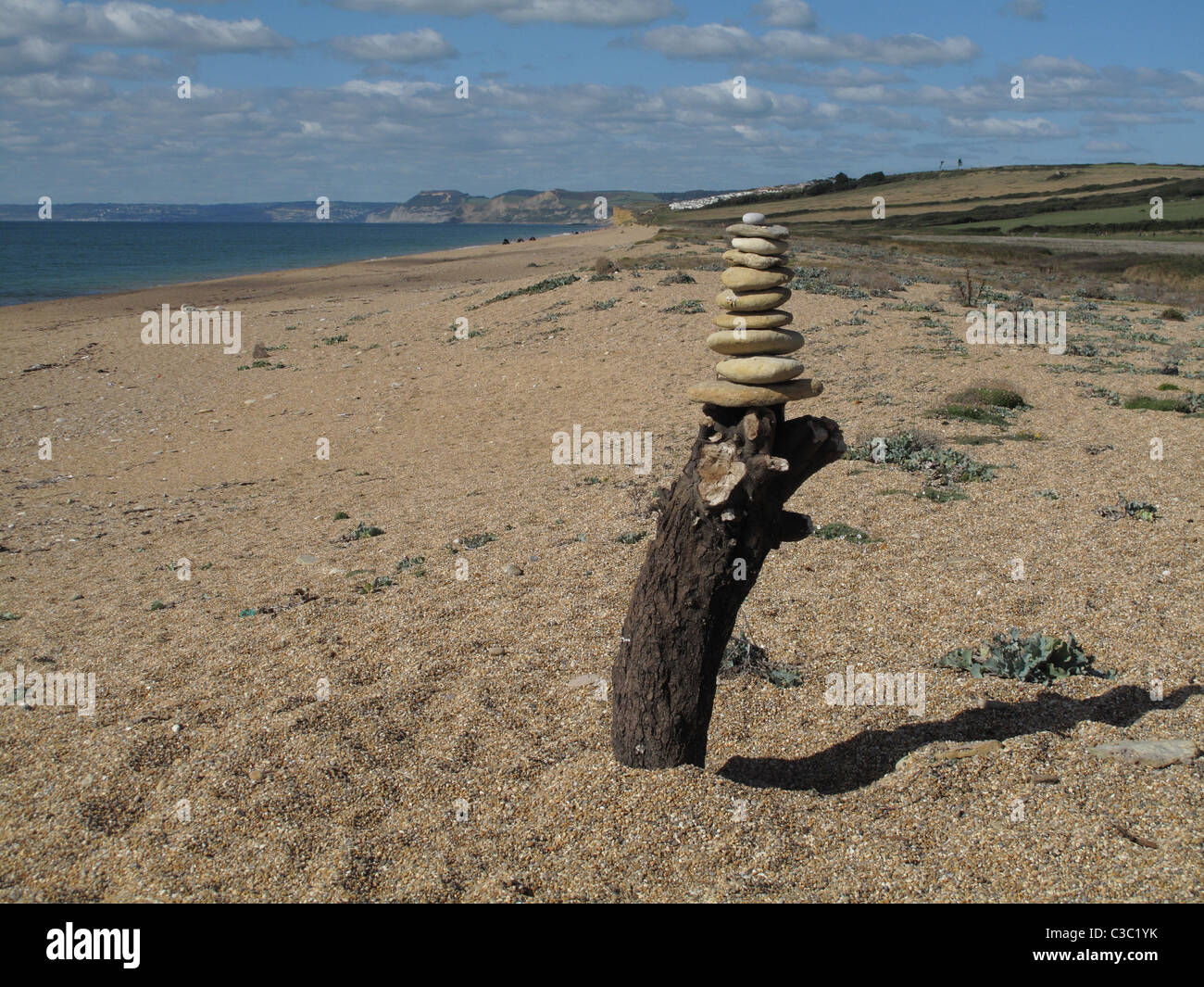 Ausgewogene Steinen auf einem hölzernen Pfosten auf Chesil Beach auf Dorset Jurassic Coast Stockfoto