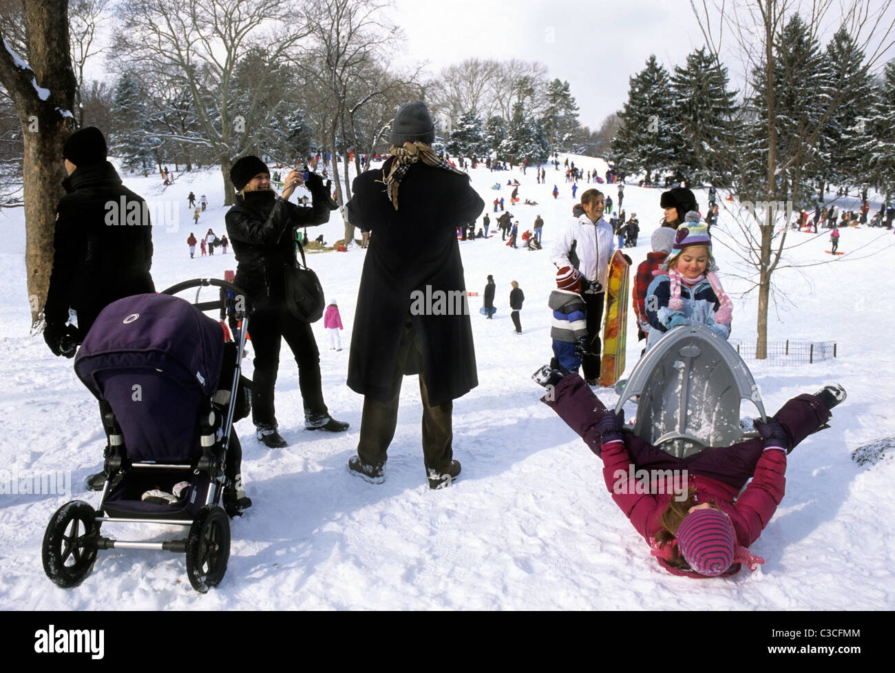New York City Gruppen von Menschen im Central Park genießen Winteraktivitäten. Familien mit Kindern spielen im Schnee auf Cedar Hill. Upper East Side. Stockfoto