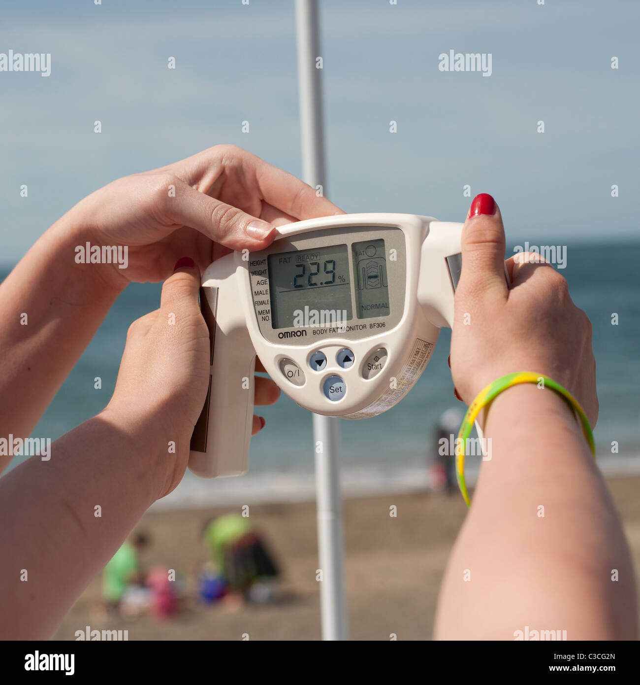 eine Person, die einen kostenlosen Checkup mit einem OMRON Hand gehalten Körperfettwaage Stockfoto