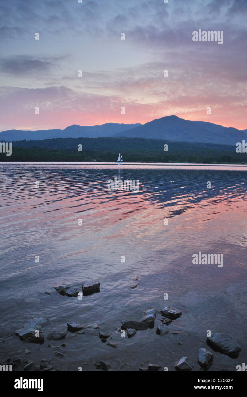 Segelboot unter altrosa rosa Himmel auf Coniston Water im englischen Lake DIstrict Stockfoto