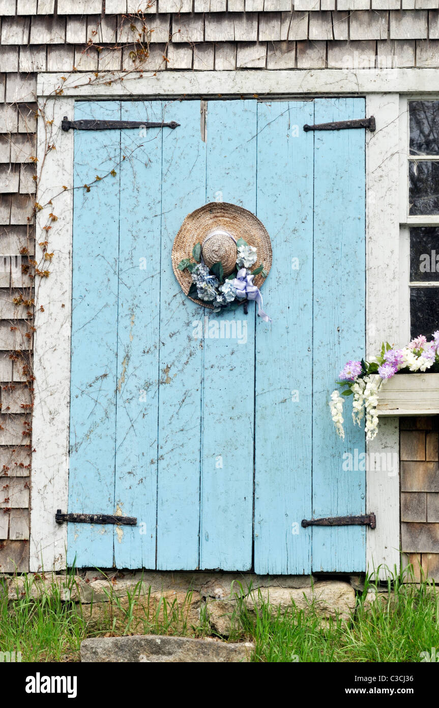 Malerische Cape Cod Scheune mit blühenden Blumenkasten und geschmückten Strohhut an Tür. USA Stockfoto