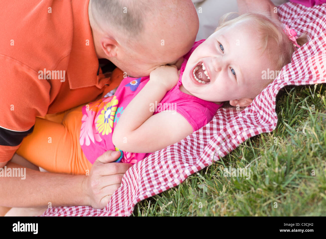 Liebende Vater kitzelt seine Tochter im Park. Stockfoto
