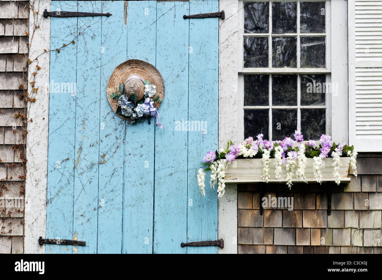 Malerische Cape Cod Scheune mit blühenden Blumenkasten und geschmückten Strohhut an Tür. USA Stockfoto