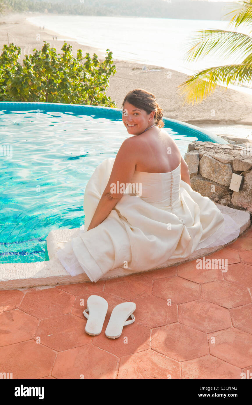 Braut sitzt mit Füßen im pool Stockfoto