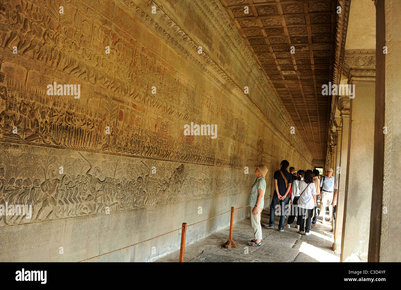 Besucher betrachten Angkor Wat Wand bedeckt mit Reliefs und Schnitzereien mit Geschichten und Charakteren aus der hinduistischen Mythologie Stockfoto
