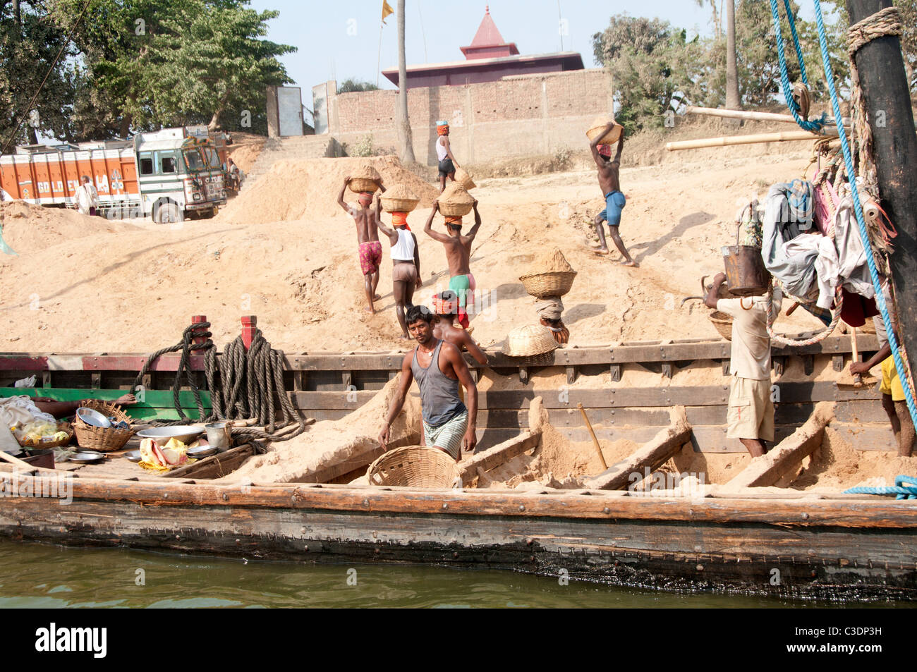 Die Diara, Bihar, Indien März 2011. Arbeiter entladen Sand von einem Boot aus. Der Sand wird von Inseln im Fluss Ganges gesammelt. Stockfoto