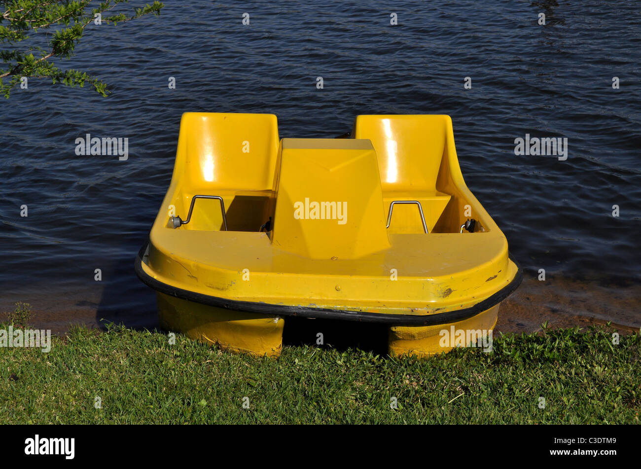 Ein gelber Tretboot auf dem Land an einem See Stockfoto