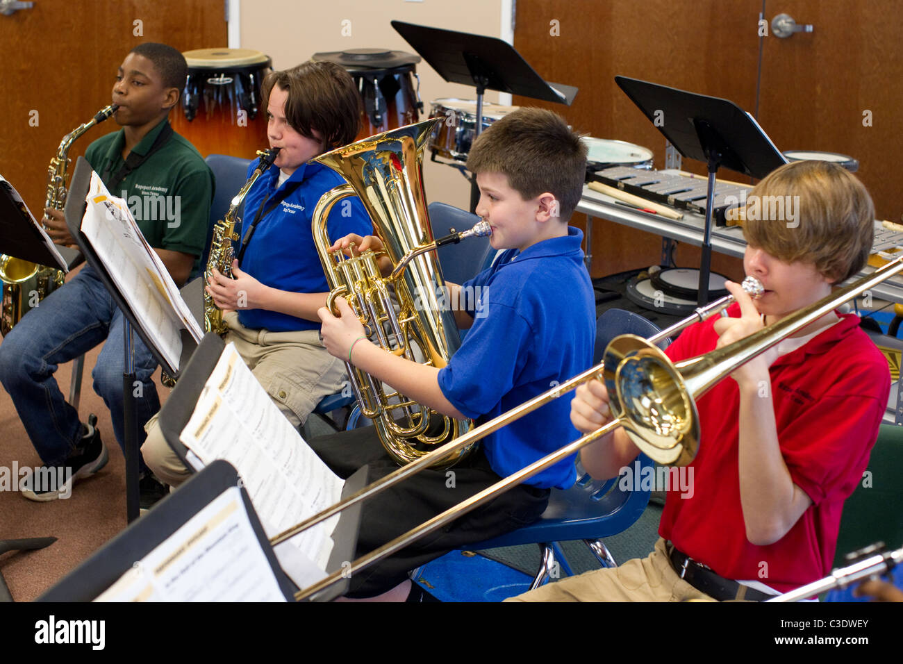 Männliche und weibliche Schülerinnen und Schüler Noten lesen und Euphonium, Posaune und Saxophon zu spielen, während Bandprobe. Stockfoto