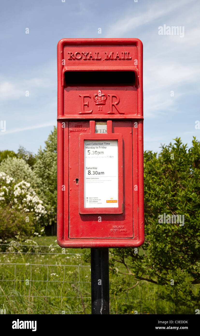 Königliche Post Briefkasten am Straßenrand in ländlicher Umgebung. Kleinen  roten Briefkasten mit Bäumen und Sträuchern blauen Himmel Wolken zeigen.  Sonniger Tag Stockfotografie - Alamy