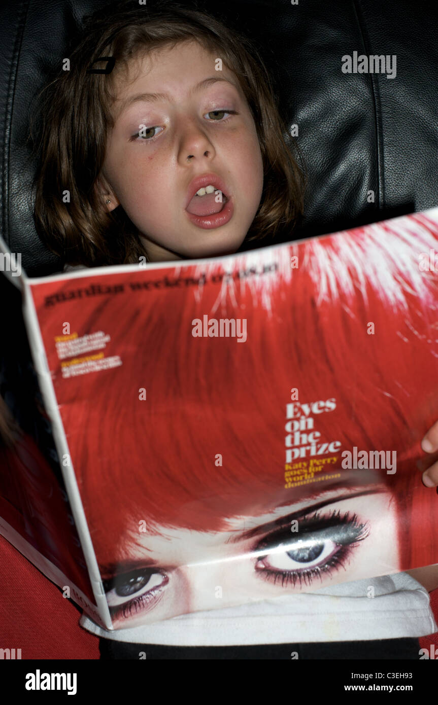 Junges Mädchen Lesen eines Artikels über Pop star Katy Perry im Guardian Magazin veröffentlicht Stockfoto