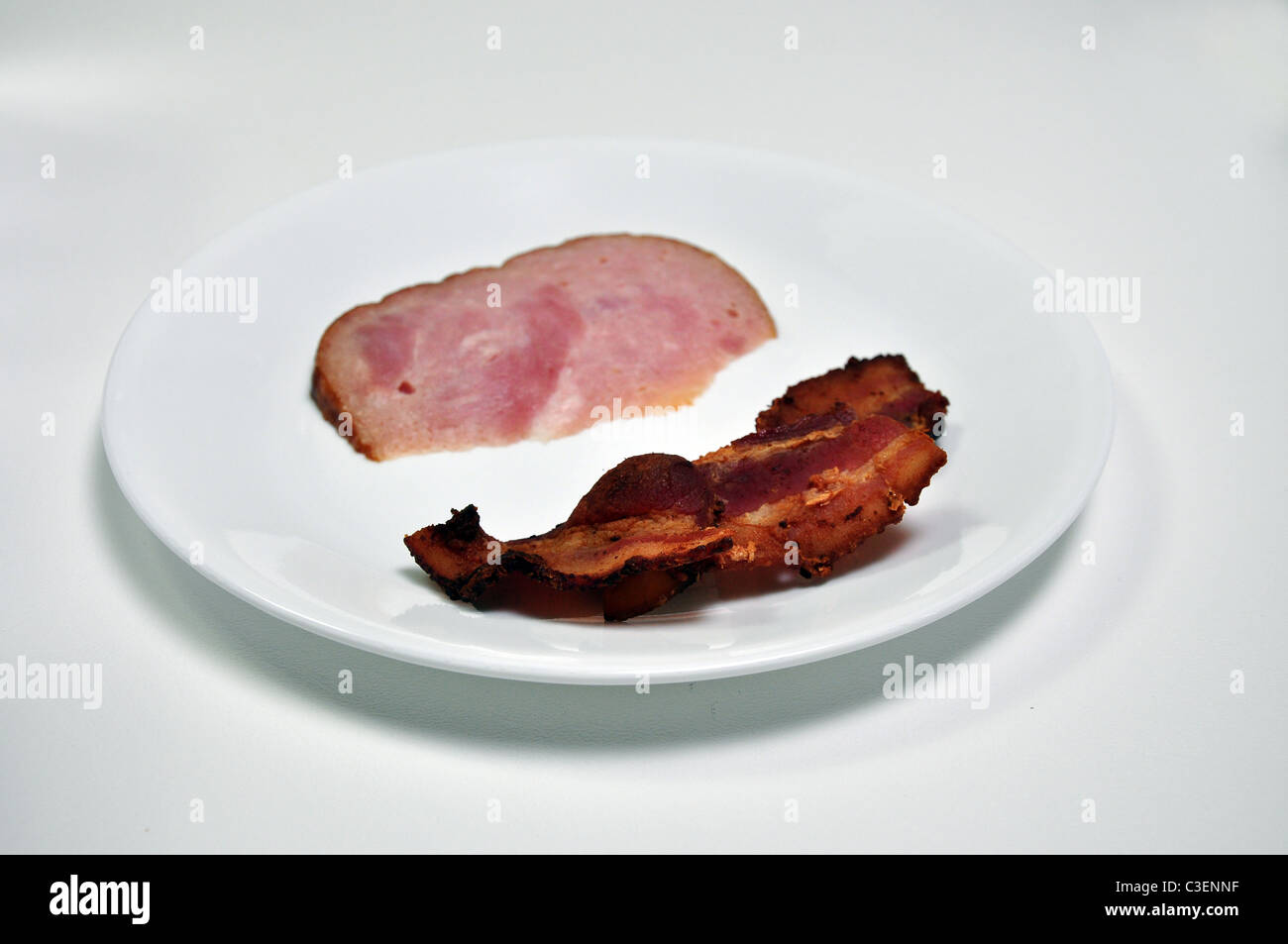 Speck und Schinken auf einem Teller mit dem Fokus auf den Speck und nicht der Schinken. Dies ist der Grund für die geringe Schärfentiefe. Stockfoto