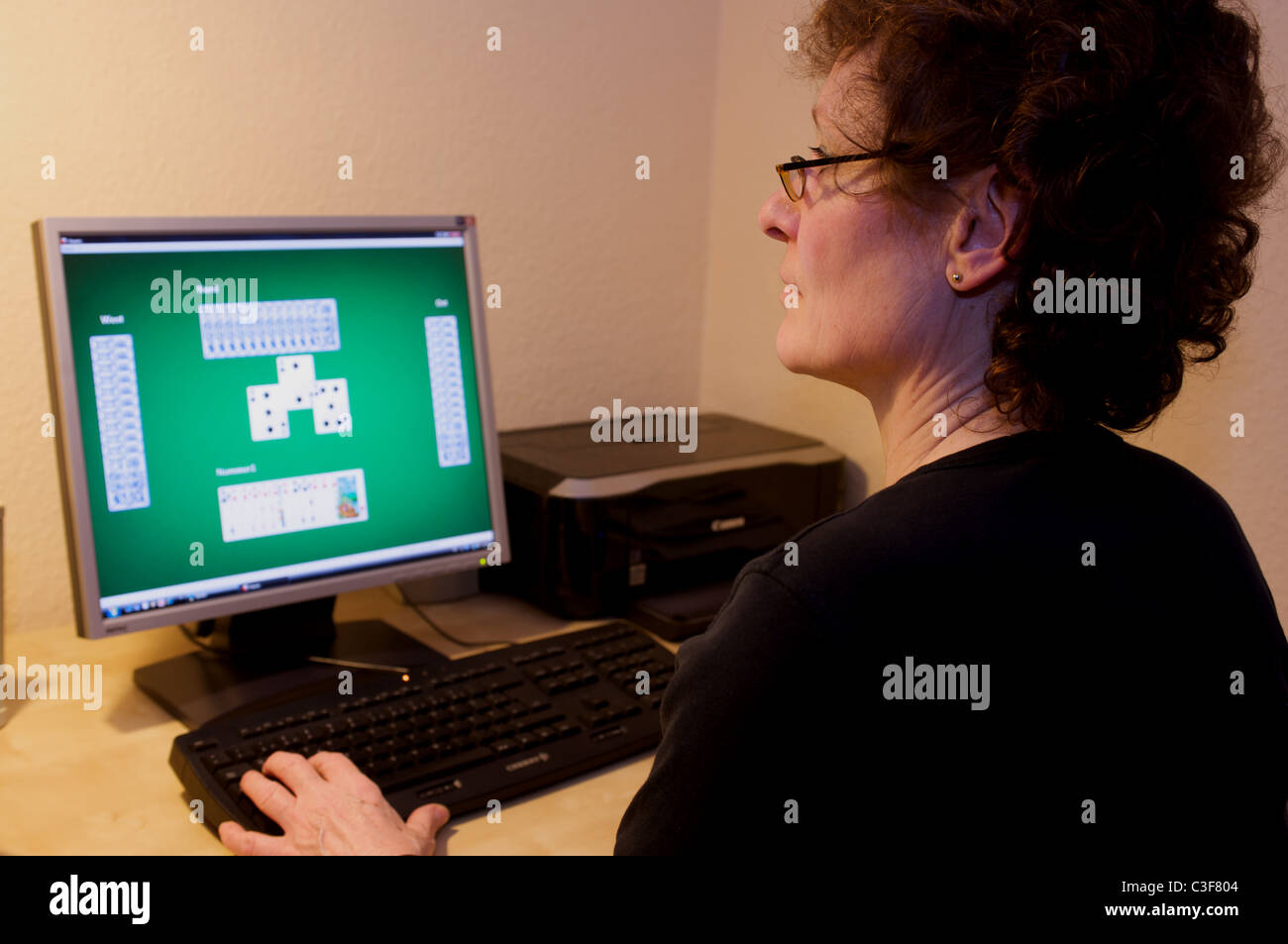 Frau Kartenspiele am Computer zu Hause Stockfoto