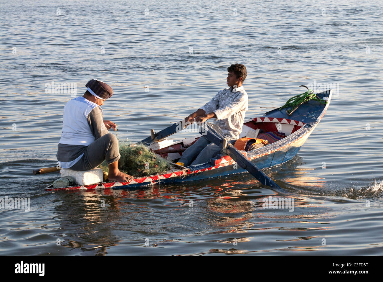 Ein kleinen hölzernen Fischerboot Arm an Wasser mit Mann Angeln und Rudern jungen umgeben leicht gebrochen, Nil, Ägypten, Afrika Stockfoto