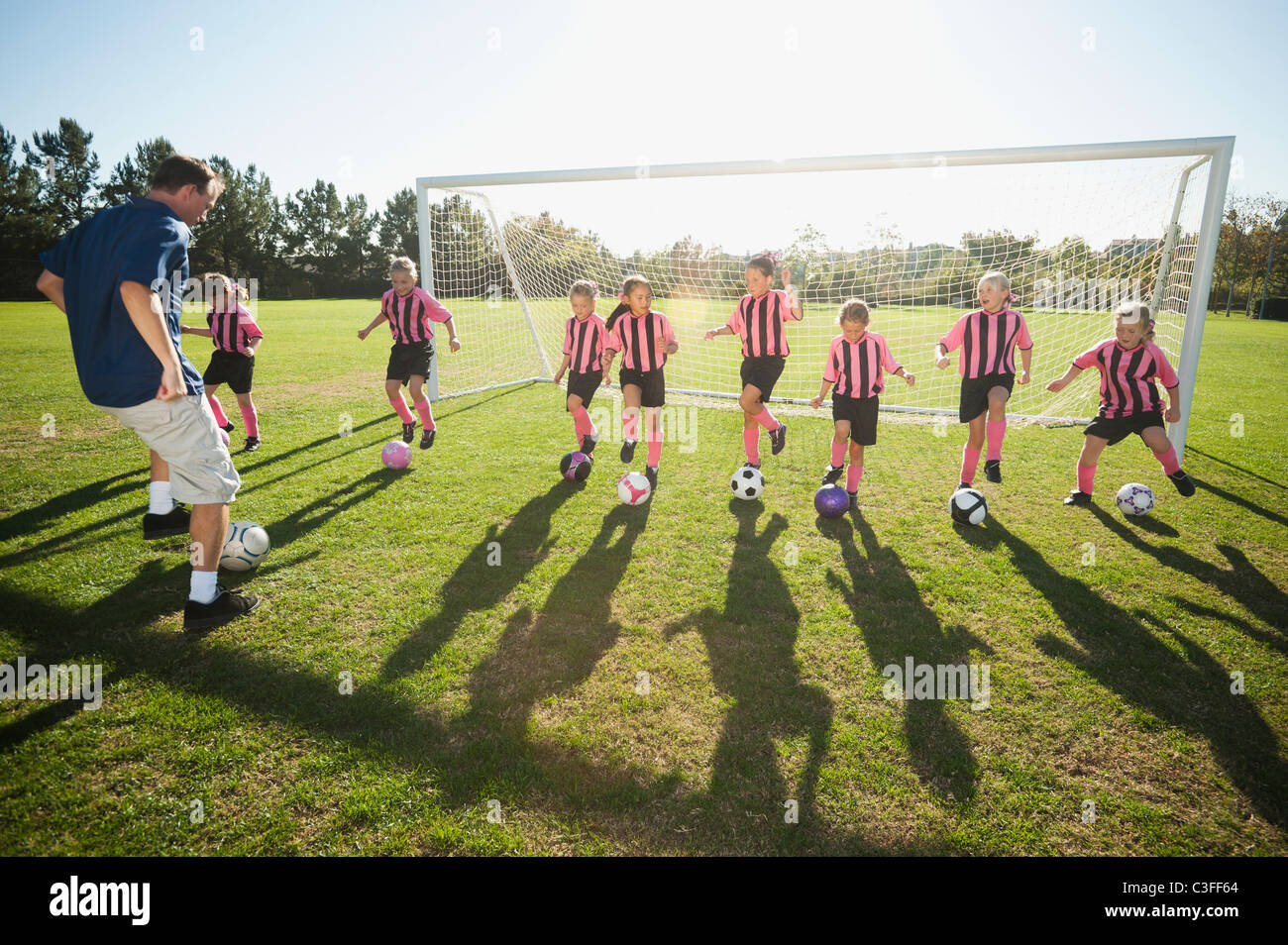 Trainer üben mit Mädchen-Fußball-Spieler Stockfoto