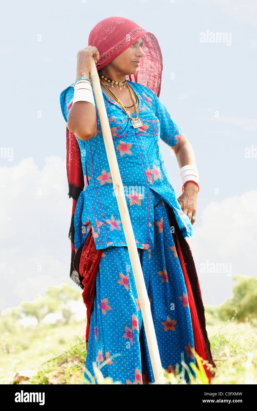 Frau, die in einem Feld mit einem Stock, Jaipur, Rajasthan, Indien Stockfoto