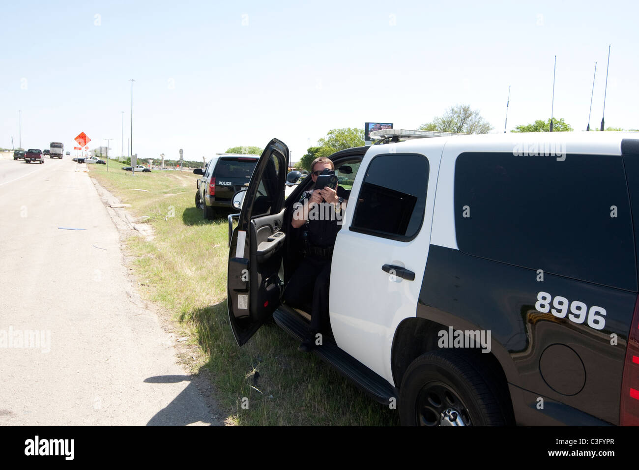 Männlicher Polizist benutzt Radar Geschwindigkeit Waffe, um Geschwindigkeitsüberschreitungen fangen Fahrer auf der Autobahn in Austin Texas USA Stockfoto