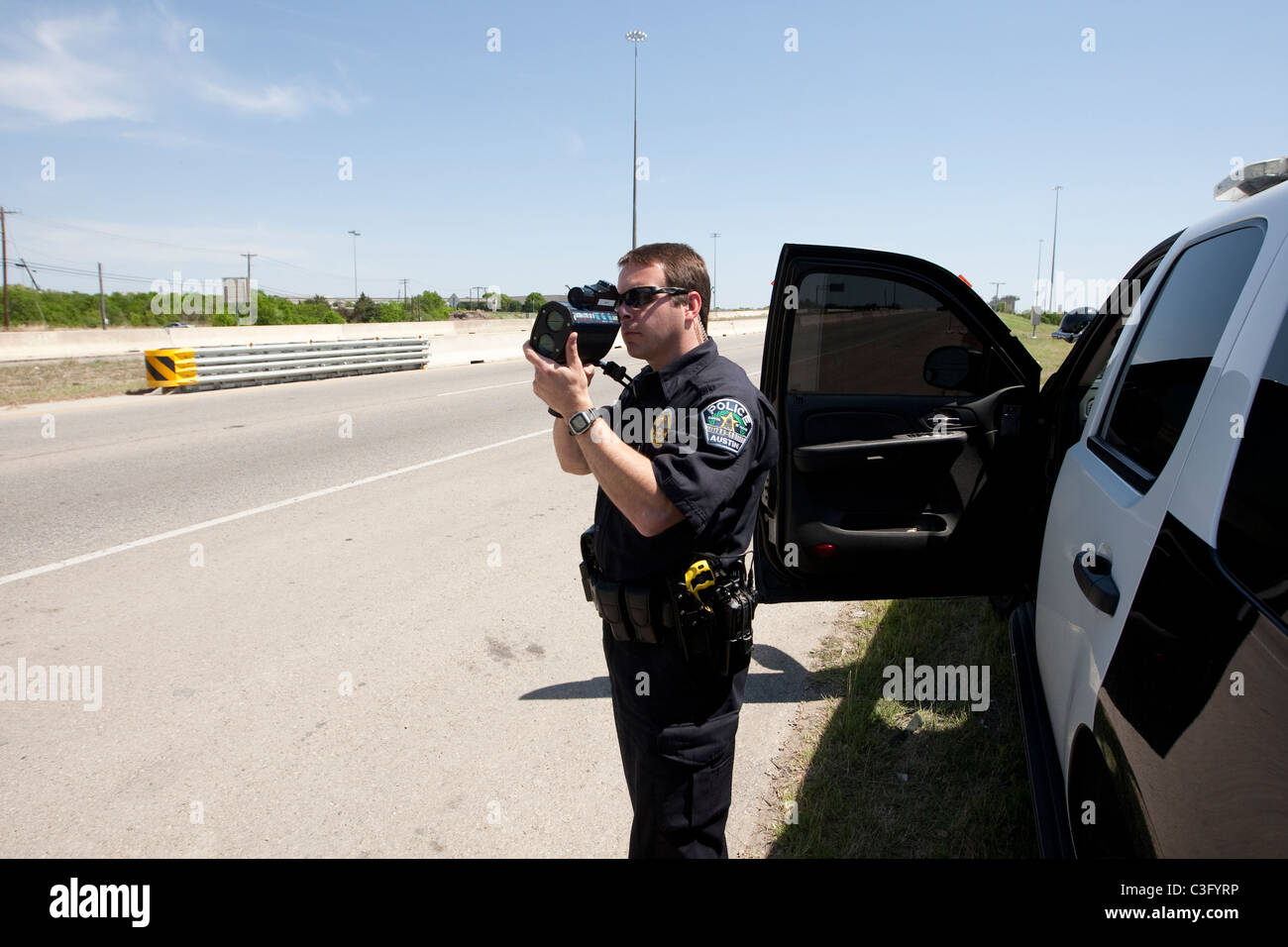 Männliche Polizeiamt benutzt Radar Geschwindigkeit Waffe, um Geschwindigkeitsüberschreitungen fangen Fahrer auf der Autobahn in Austin Texas USA Stockfoto