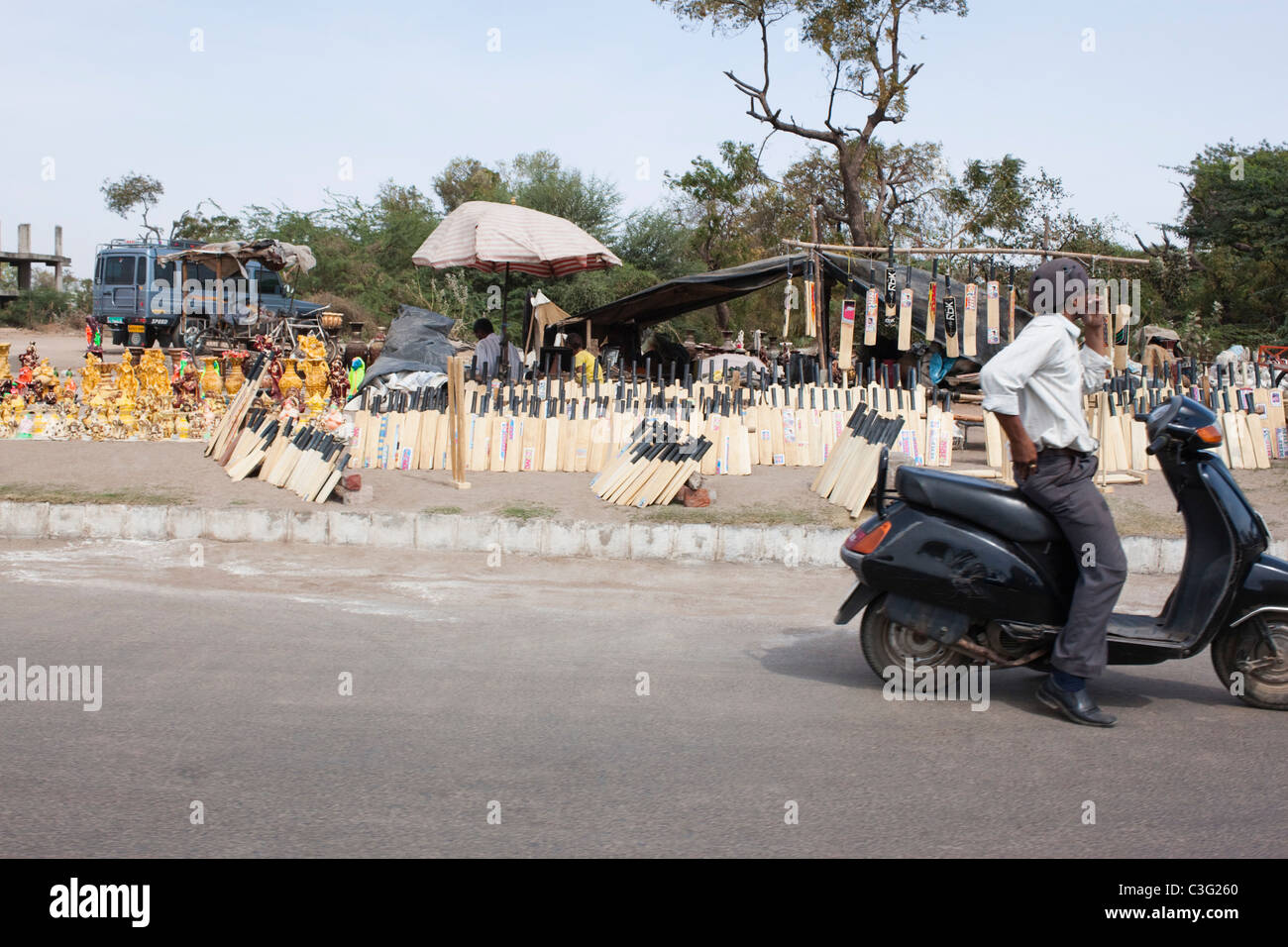 Mann sitzt auf einem Roller auf der Straße, Ahmedabad, Gujarat, Indien Stockfoto