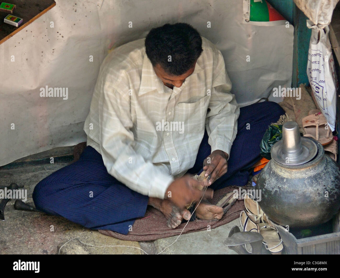 Eine Kaste, Schuster, reparieren Schuhe am Straßenrand, Indien Stockfoto