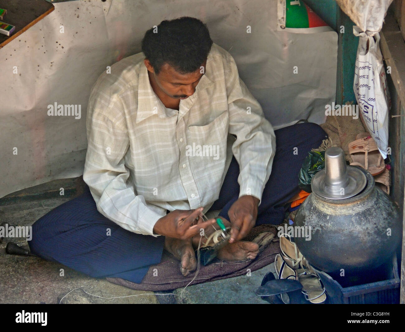 Eine Kaste, Schuster, reparieren Schuhe am Straßenrand, Indien Stockfoto