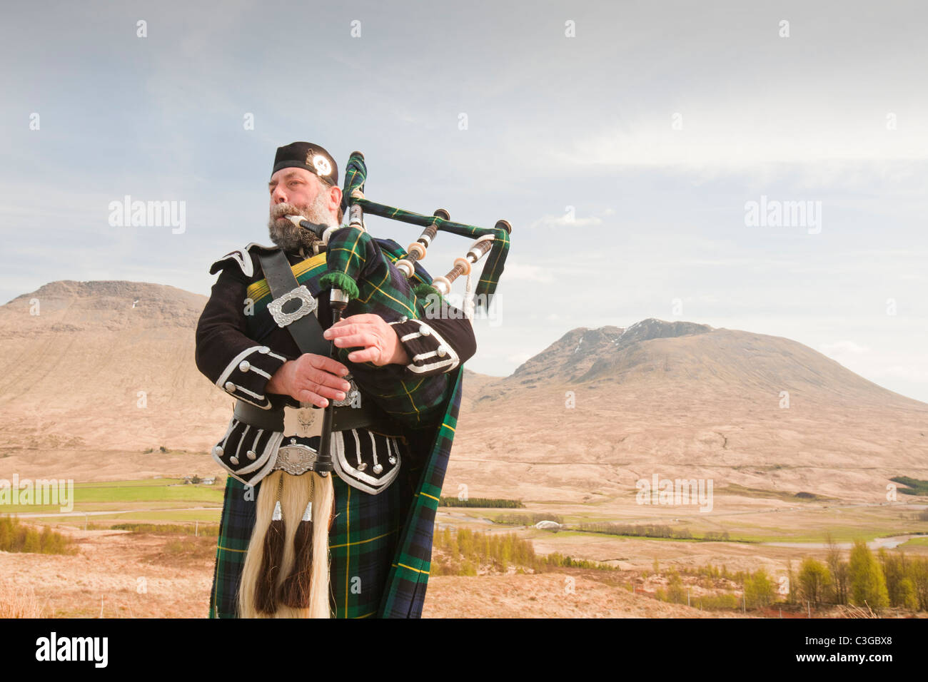 Eine schottische Piper in traditioneller Tracht als Straßenmusikant auf Rannoch Moor in Argyl, Scotland, UK. Stockfoto
