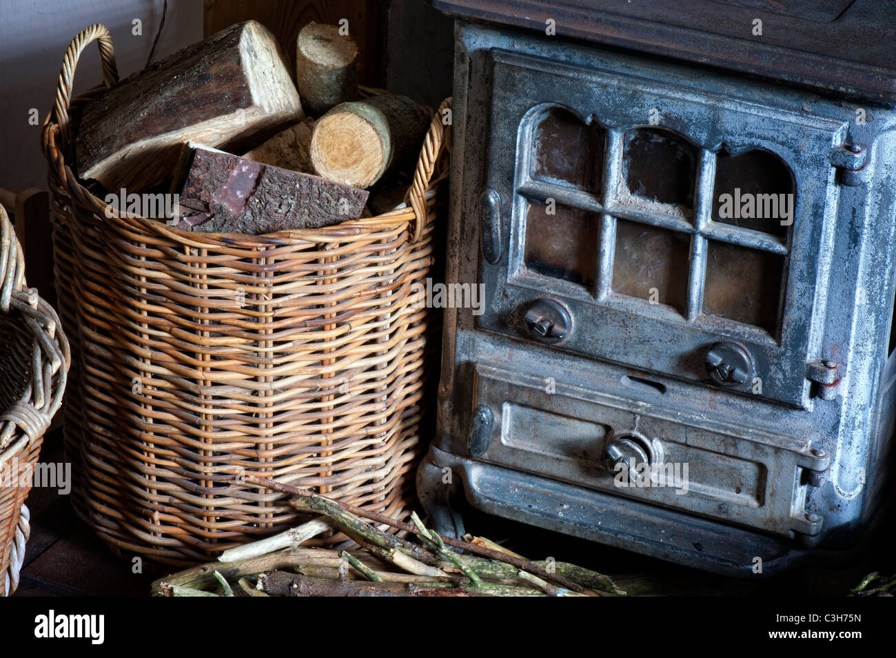 Kaminofen und einen Korb von Protokollen in einem Landhaus. Großbritannien Stockfoto
