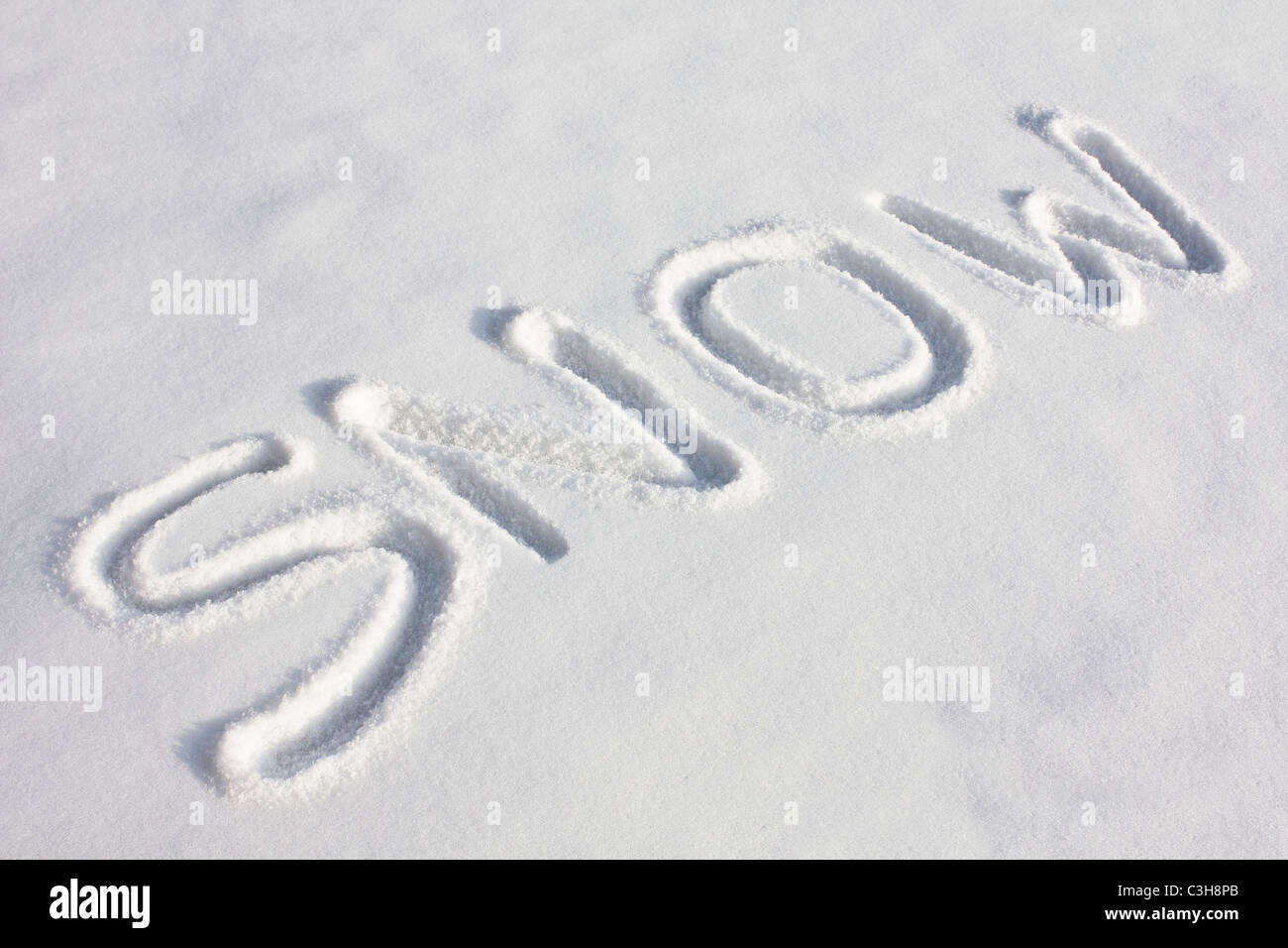 Das Wort "Schnee" eingeprägt in einem frisch verschneiten Feld unter hellem Sonnenlicht Stockfoto