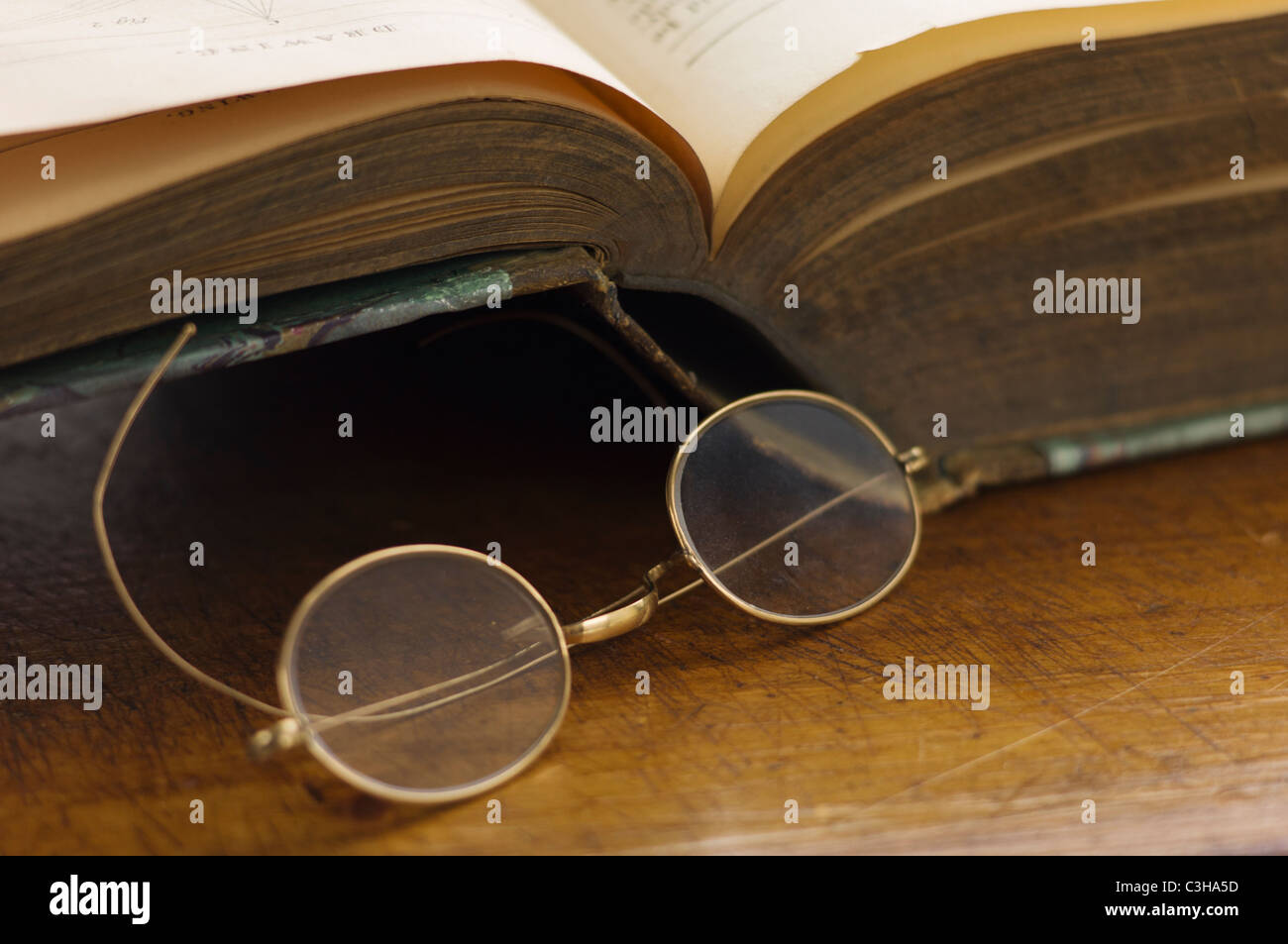 Schließen sich antike Runde Brille und Buch öffnen Stockfoto