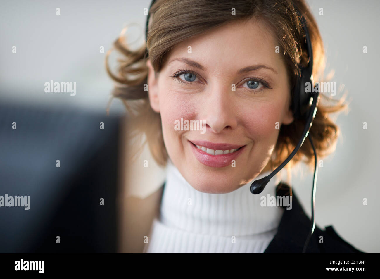 Portrait von lächelnden Frau mit Kopfhörer im Kundenbüro Stockfoto