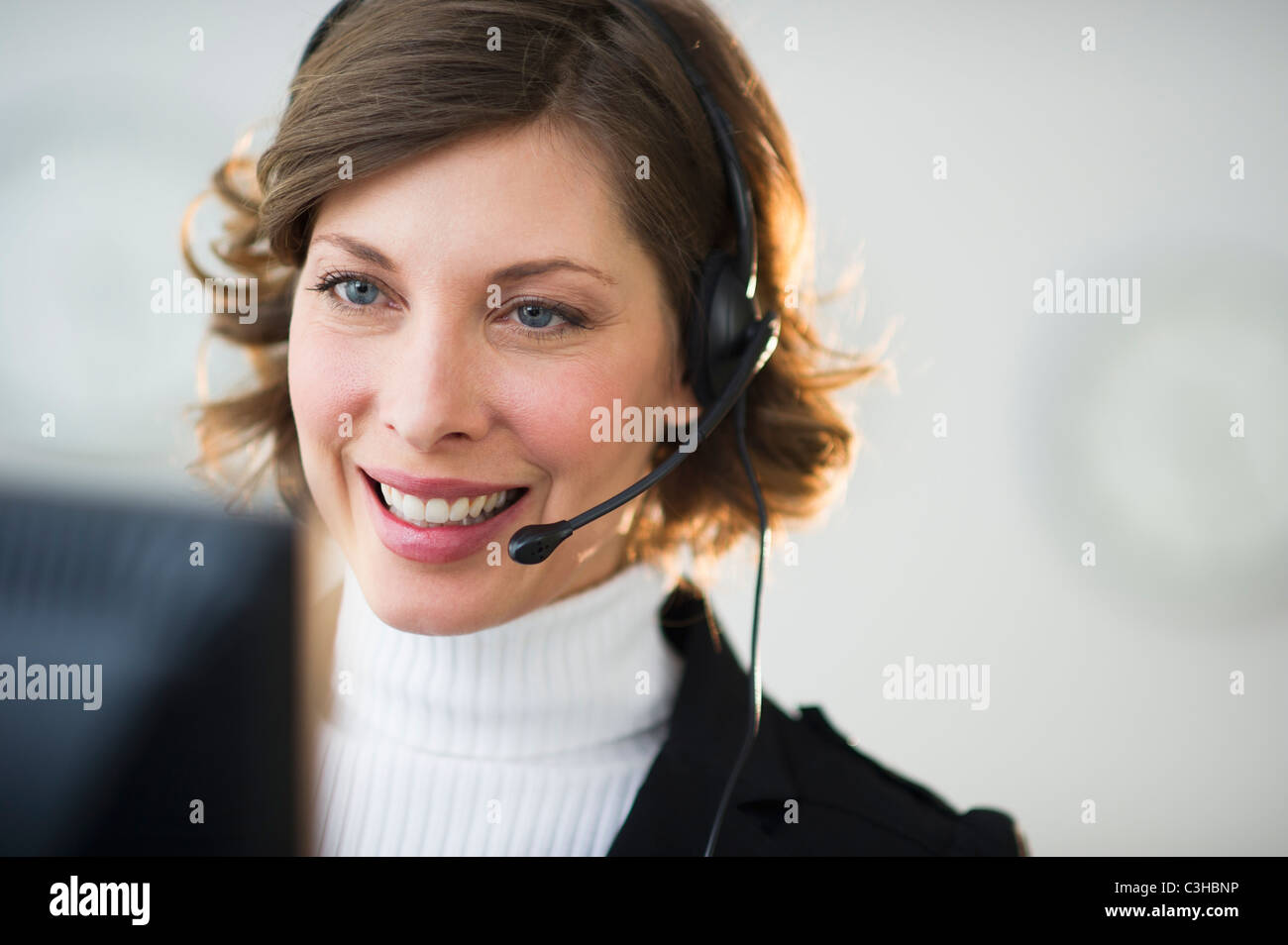 Lächelnde Frau mit Kopfhörer im Kundenbüro Stockfoto