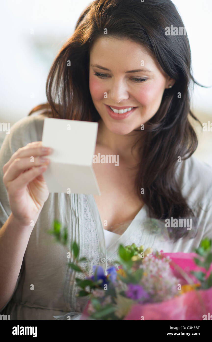 Junge Frau hält Bukett und lesen Grußkarte Stockfoto