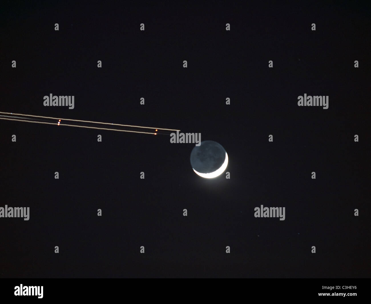 vergrößerte Ansicht einer Jet-Strecke erscheinen, um die Position der Mondsichel am westlichen Nachthimmel zu nähern Stockfoto