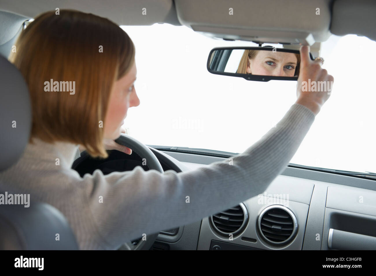 Frau Auto fahren und Spiegel einstellen Stockfoto