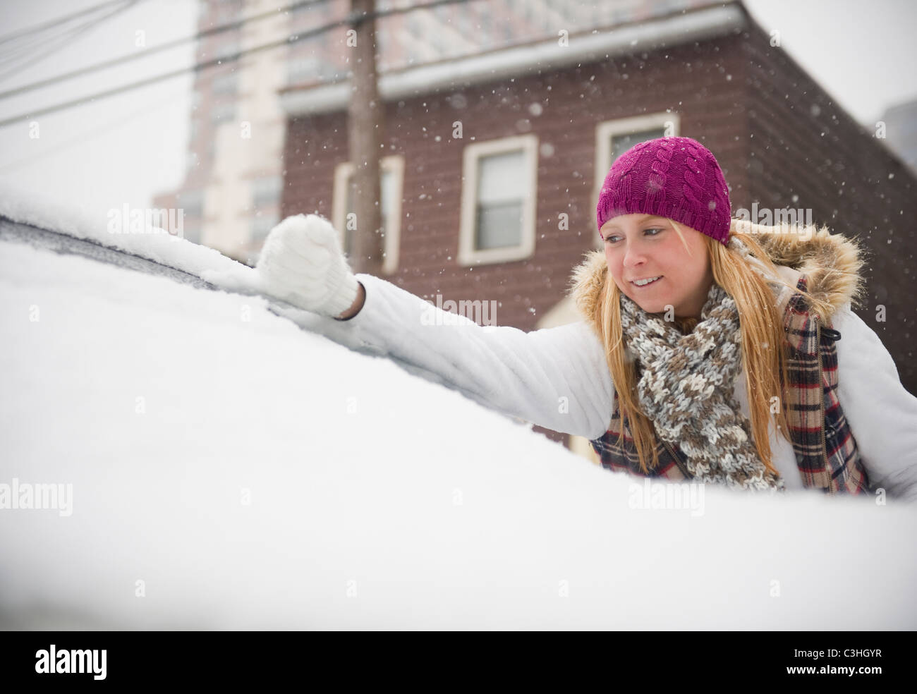 Frau räumt mit einem Besen Schnee aus einem Auto 4543491 Stock