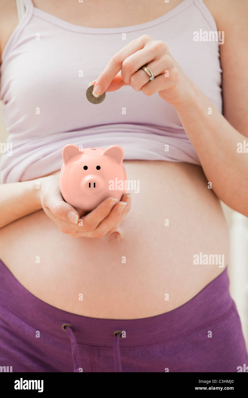 Schwangeren Frauen, Münze in rosa Sparschwein Stockfoto