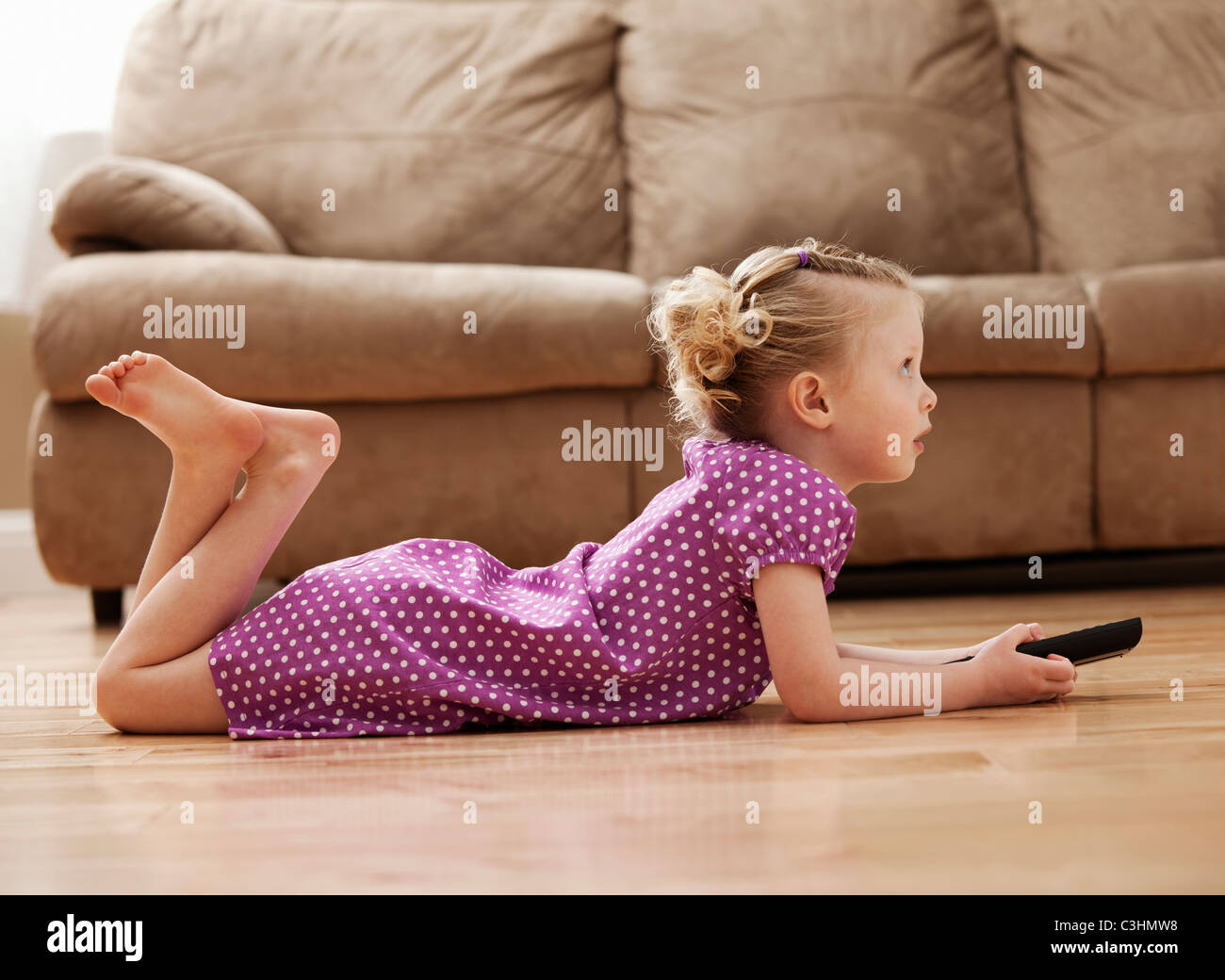 Mädchen (2-3) auf Boden liegend, vor dem Fernseher Stockfoto
