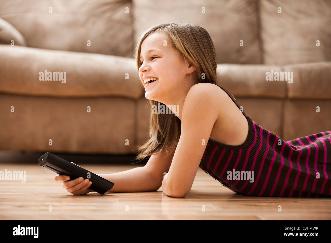 Mädchen (10-11) auf Boden liegend, vor dem Fernseher Stockfoto