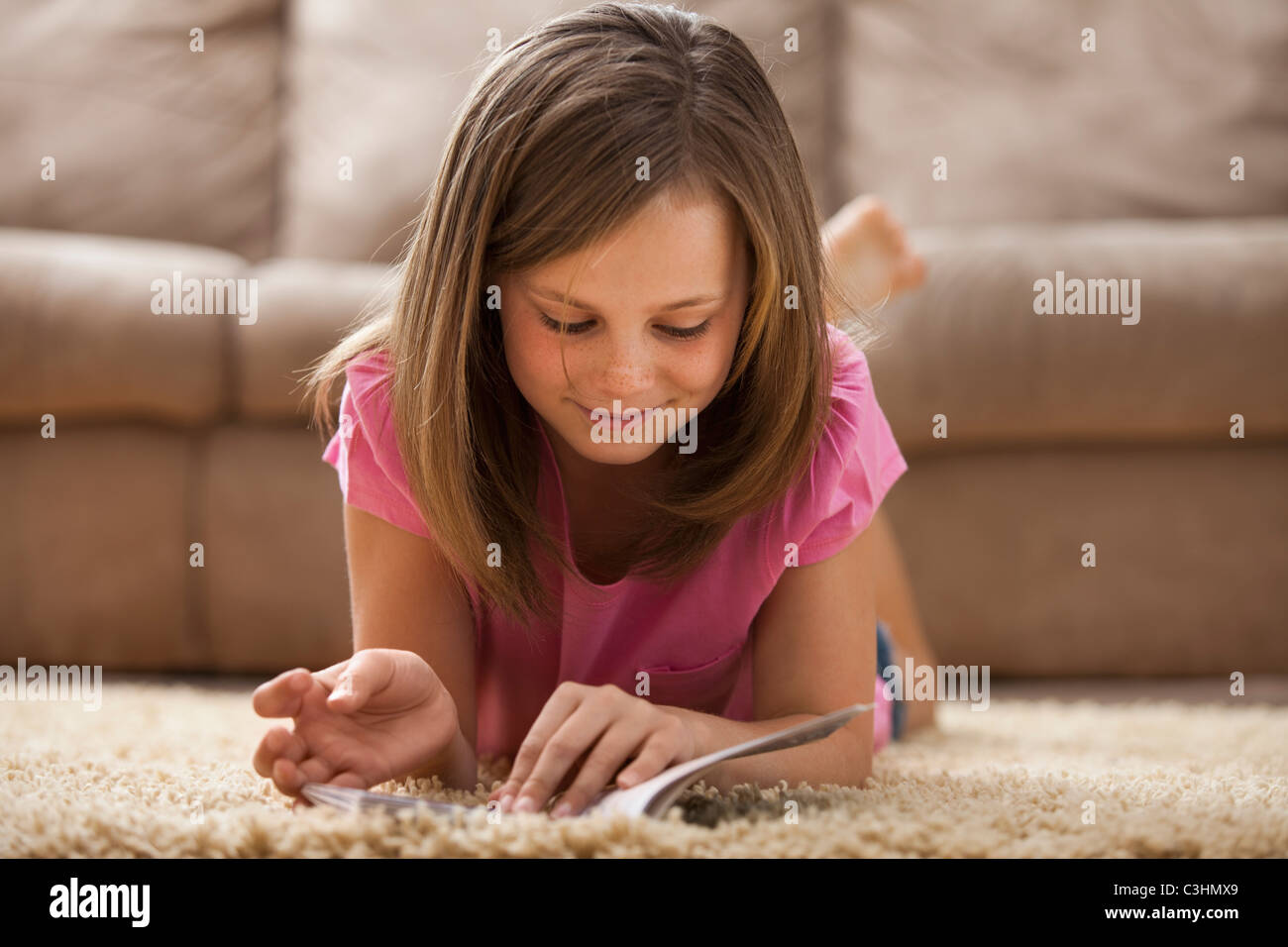 Mädchen (10-11) liegen auf Teppich, Buch lesen Stockfoto